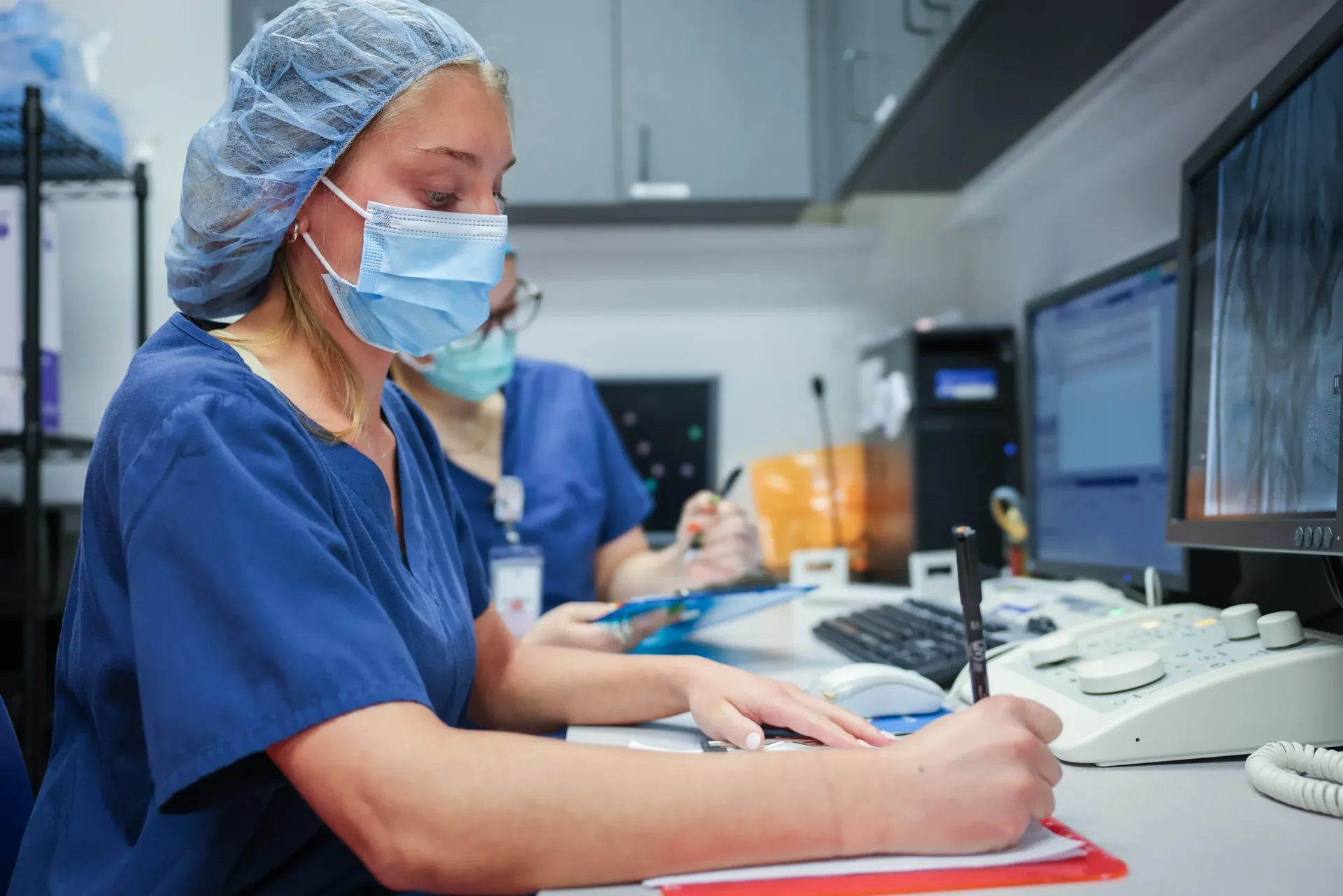 Synchrony Labs staff recording study data by hand at the procedure suite workstation
